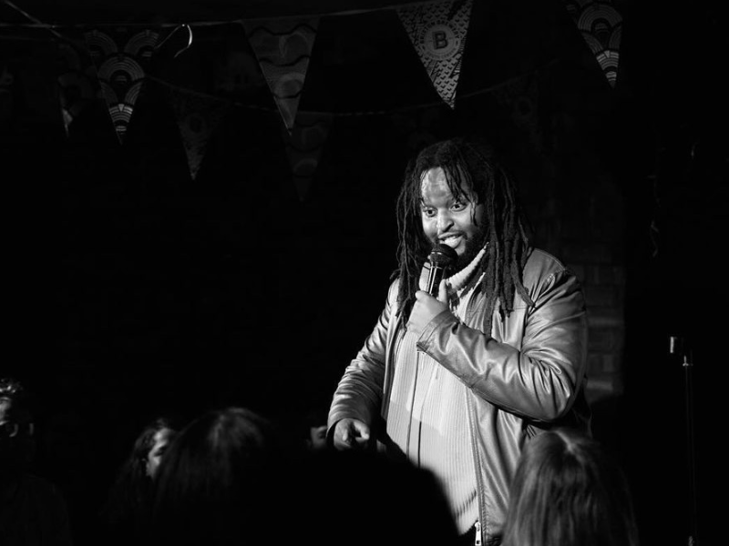 Black and white image of man with microphone on stage