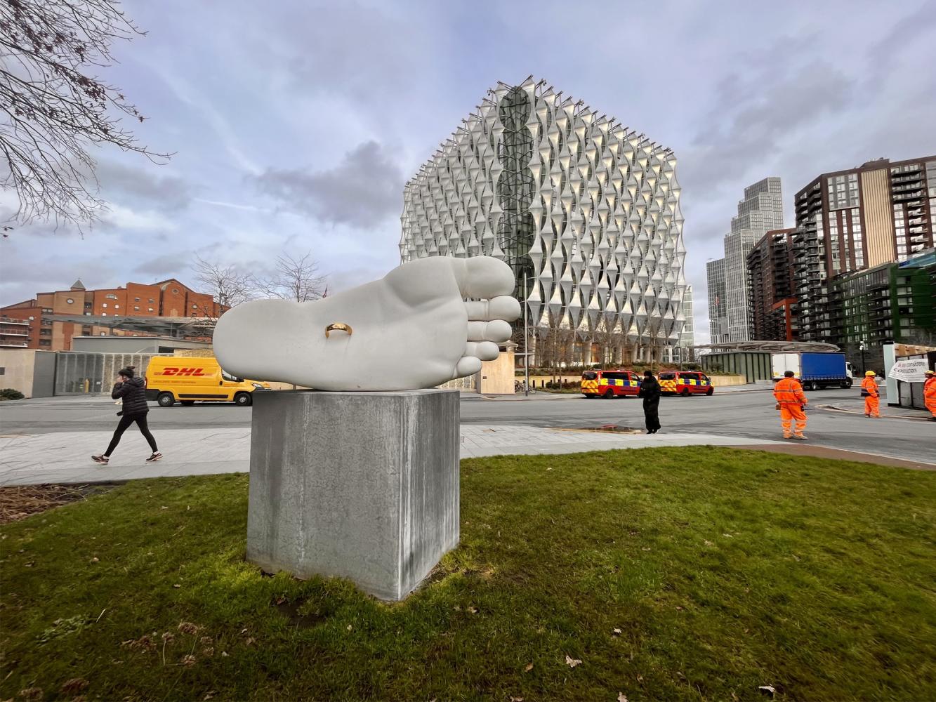 Sculpture of foot with metal ring in the sole in the foreground. US Embassy building seen in the background.