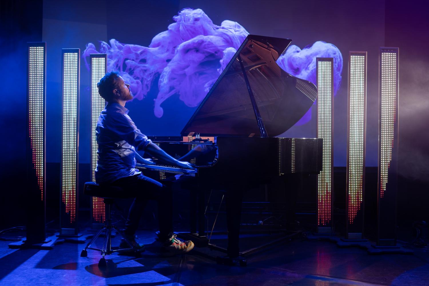 Larkhall plays the piano in front of projected visuals