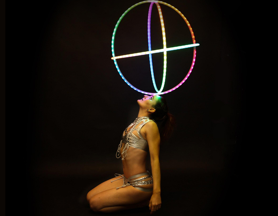 Image of a woman, Laura Loops, kneeling on the floor and balancing hoops on her nose.