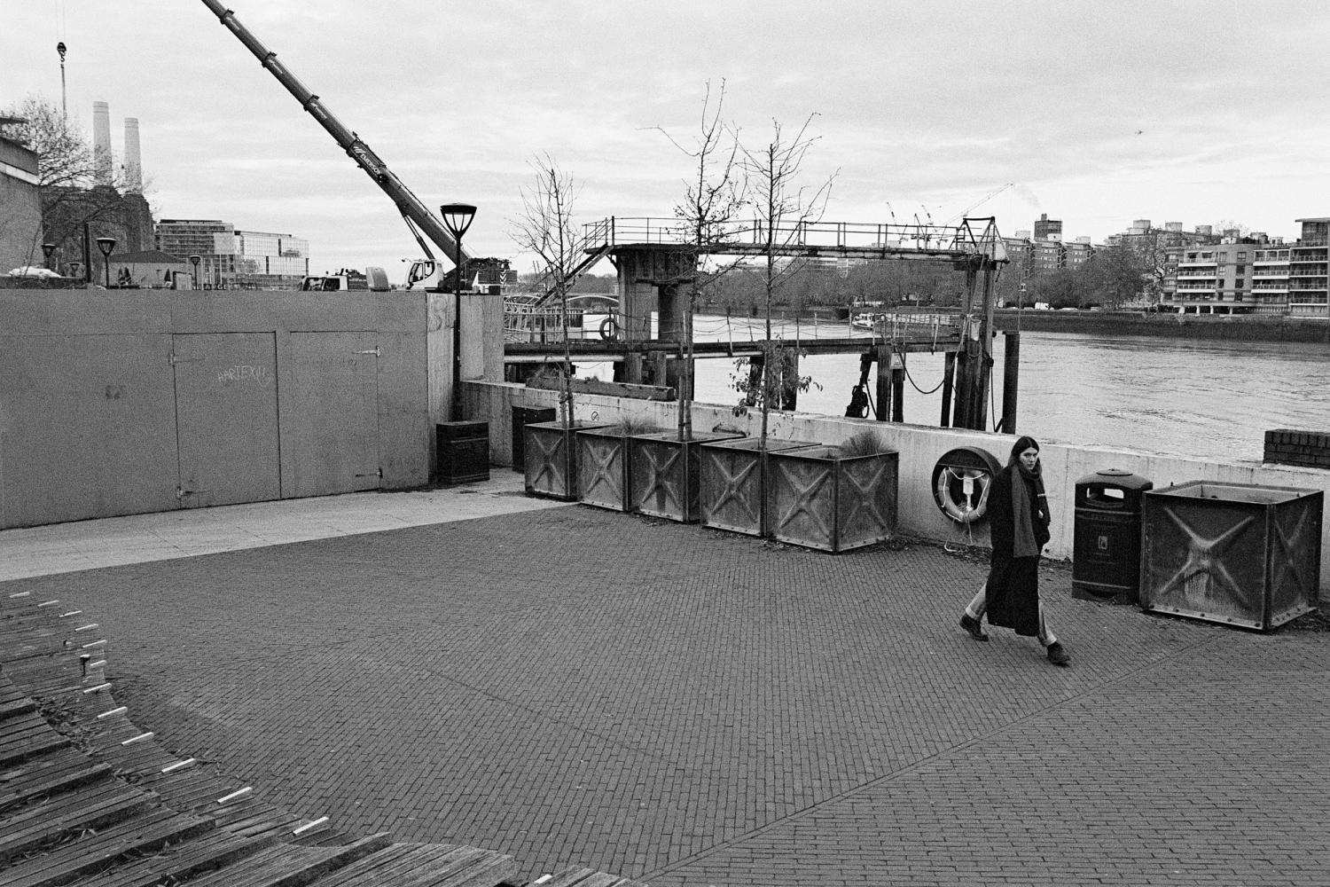 A photograph of the Thames Walk in Nine Elms. The performer is walking to trace a small square.