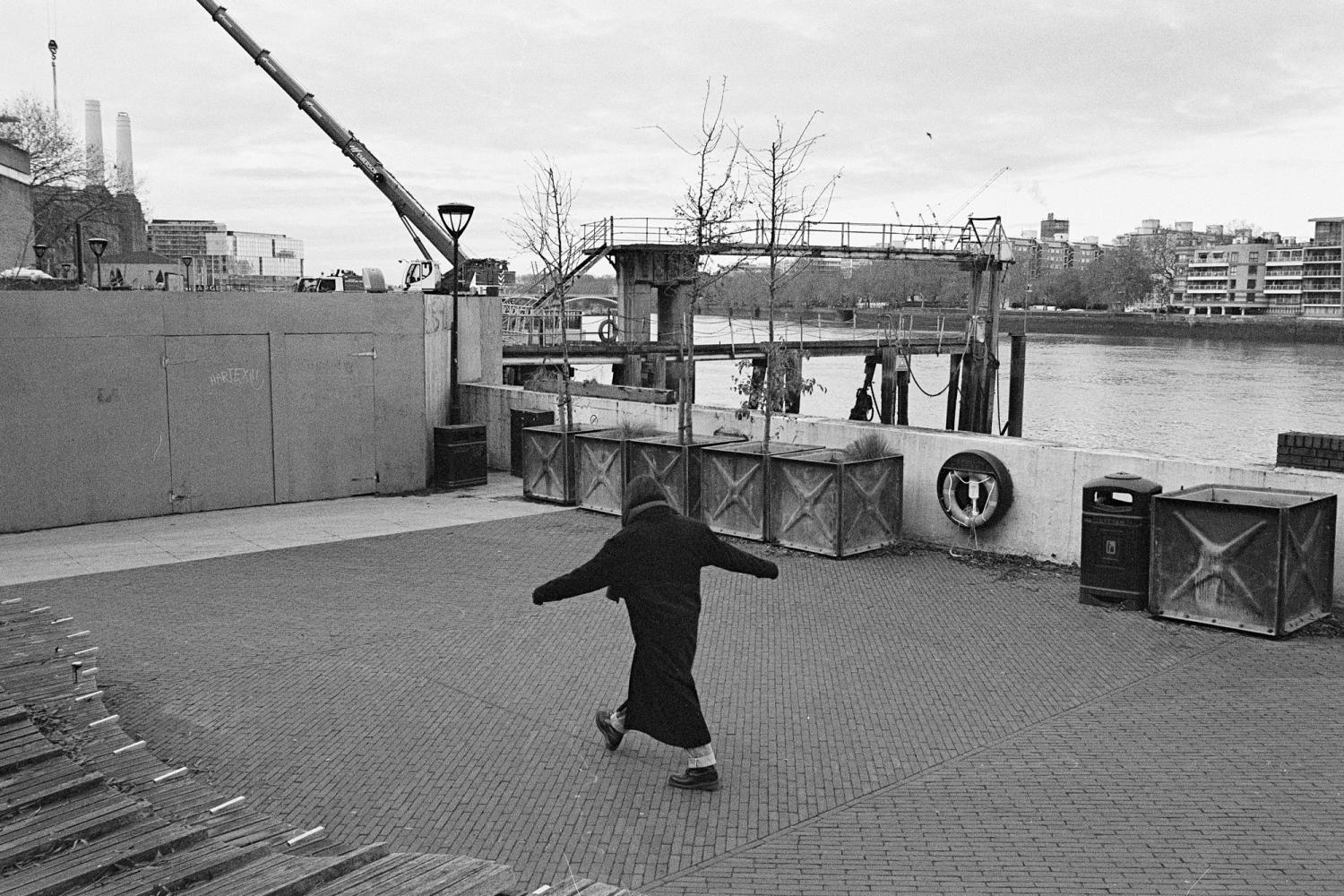 A photograph of the Thames Walk in Nine Elms. The performer is walking to trace a small square.