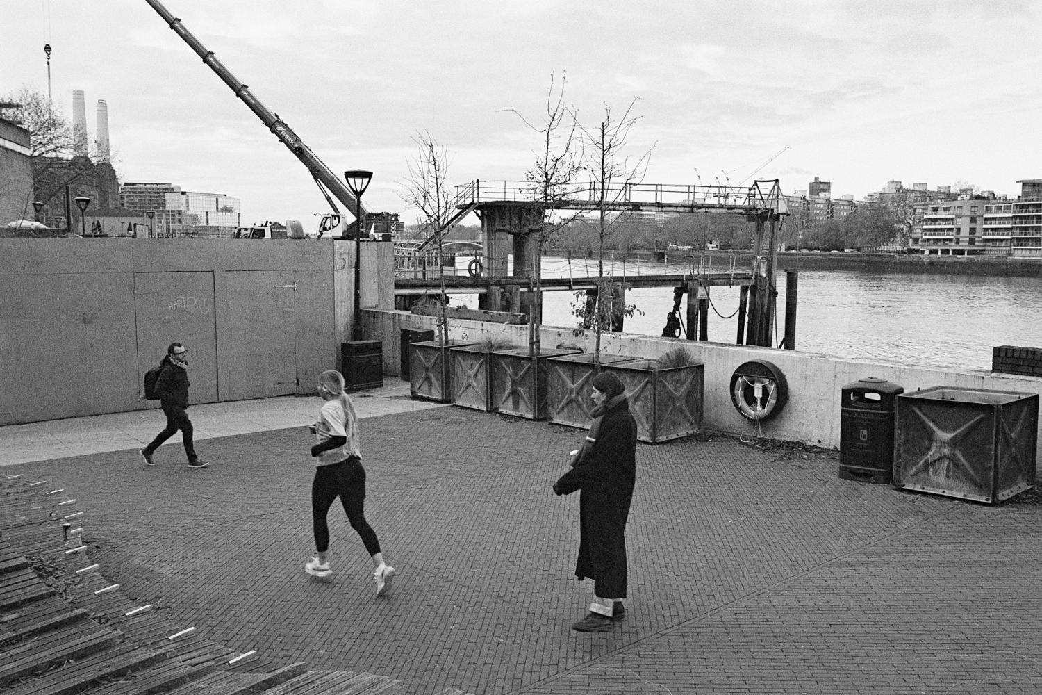 A photograph of the Thames Walk in Nine Elms. The performer is walking to trace a small square.